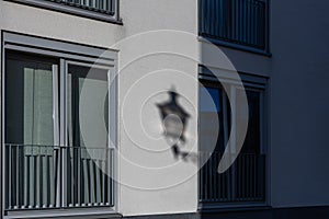 A shadow of a typical Maastricht street lamp on the facade of an appartment building making it looks like to lantern is attached t