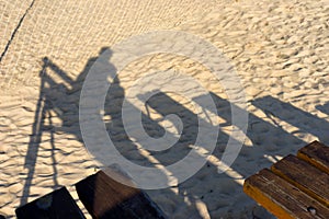 The shadow of the viewer on a bench on the beach at the net