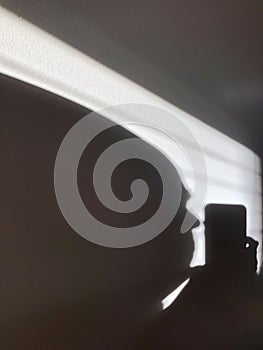 Shadow on the wall.  A man's head looks at the phone. Silhouette.  Abstraction.