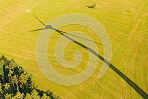 A shadow of a windmill on the yellow field. Renewable energy production concept