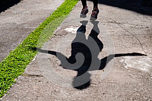 shadow of woman with black clothing jumping rope in the park