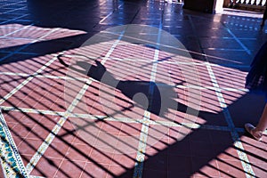 Shadow of a woman classical ballet dancer making figures on metal gratings against the light