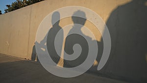 Shadows of argued couple sitting back to back as male silhouette passing and woman leaving man. Unrecognizable boyfriend