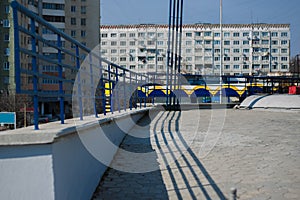 Shadows of fencing over background of old buildings.