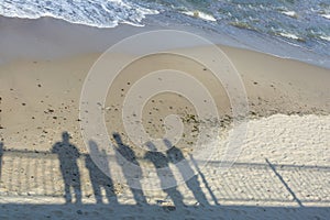 Shadows of group of people on the seashore. Concept of recollection, pandemic, departure to another reality