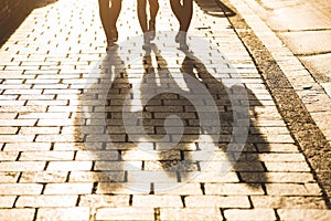 Shadows of three girls walking on a sidewalk in the city