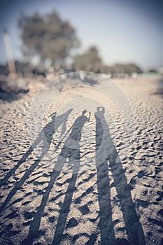 Shadows of three people on a beach