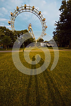 Shadows of the two people on the grass against the ferris wheel in the park in Vienna, Austria