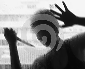 Shadowy figure with a knife behind glass