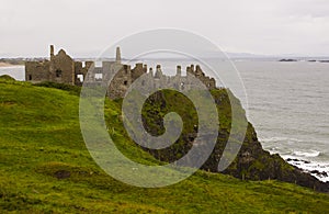 The shadowy ruins of the medieval Irish Dunluce Castle on the cliff top overlooking the Atlantic Ocean in Ireland