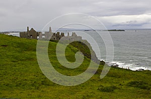 The shadowy ruins of the medieval Irish Dunluce Castle on the cliff top overlooking the Atlantic Ocean in Ireland