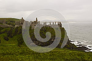 The shadowy ruins of the medieval Irish Dunluce Castle on the cliff top overlooking the Atlantic Ocean in Ireland