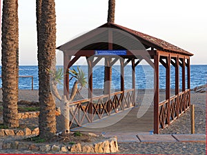 Shady beach hut under palm trees with Mediterranean sea in southern Spain photo