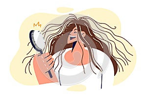 Shaggy woman is holding comb and laughing, seeing electrified hair sticking out in directions photo