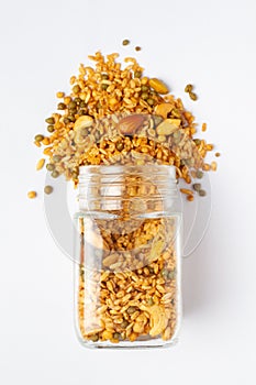 Shahi Mixture spilled out and in a glass jar, made with peanut, cashew, corn flakes, almonds.