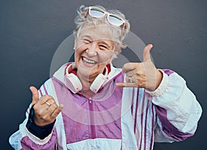 Shaka sign, portrait and senior woman in retirement standing by gray wall with a smile or happiness. Happy, fun and