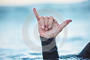 Shaka, surf and man in ocean with hand sign outdoor in nature while on vacation in Australia. Surfing culture, hang