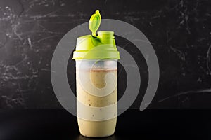 Shaker with fruit and protein drink. Shaker isolate on a dark background