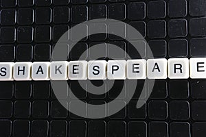 Shakespeare text word title caption label cover backdrop background. Alphabet letter toy blocks on black reflective background. Wh