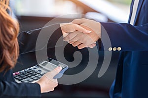 [shaking hands in auto show] auto business, car sale, deal, gesture and people concept, buy new cars that make sales agreements
