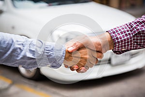 Shaking hands on car background.