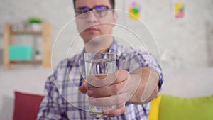 Shaking hands of a man holding a glass of water