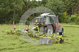 Shaking of the mown grass with red tractor with Ted