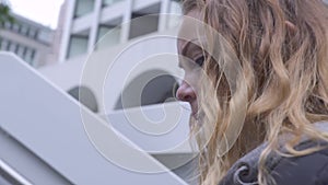 Shaking shooting face young woman going up stairs in modern city park. Close up face curly red haired woman walking up