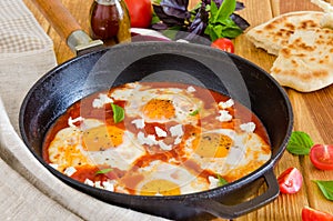 Shakshouka, dish of eggs poached in a sauce of tomatoes, chili, onions in the pan.