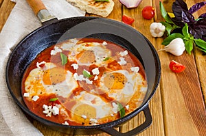 Shakshouka, dish of eggs poached in a sauce of tomatoes, chili, onions in the pan.