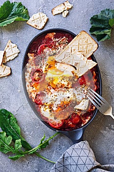 Shakshouka - Middle eastern traditional dish with poached eggs in tomato sauce, grey background