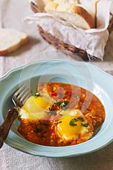 Shakshuka with bread on a wooden table. Middle eastern traditional dish. Homemade. Selective focus.