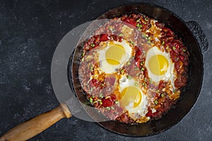 Shakshuka, fried eggs with tomatoes, onion, red pepper and spices in cast iron pan