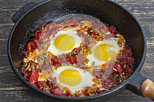 Shakshuka, fried eggs with tomatoes, onion, red pepper and spices in cast iron pan