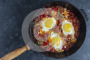 Shakshuka, fried eggs with tomatoes, onion, red pepper and spices in cast iron pan