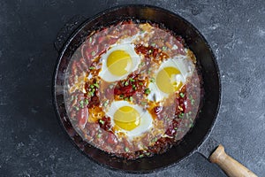 Shakshuka, fried eggs with tomatoes, onion, red pepper and spices in cast iron pan