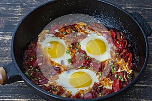 Shakshuka, fried eggs with tomatoes, onion, red pepper and spices in cast iron pan