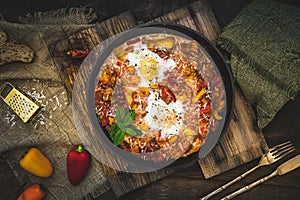 Shakshuka in an iron pan on wooden background