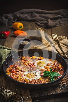 Shakshuka in an iron pan on wooden background