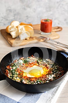 Shakshuka Israeli breakfast: stewed vegetables, scrambled eggs, tomato juice and slices of homemade bread