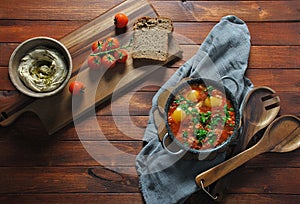 Shakshuka in pan with humus on a brown wooden background.