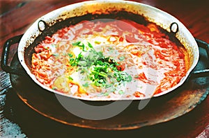 Shakshuka. Traditional jewish food and middle eastern cuisine recipe. Fried eggs, tomatoes, bell pepper and parsley in a