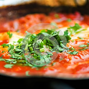 Shakshuka. Traditional jewish food and middle eastern cuisine recipe. Fried eggs, tomatoes, bell pepper and parsley in a