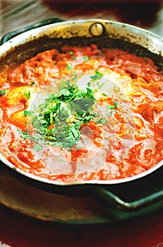 Shakshuka. Traditional jewish food and middle eastern cuisine recipe. Fried eggs, tomatoes, bell pepper and parsley in a