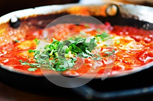 Shakshuka. Traditional jewish food and middle eastern cuisine recipe. Fried eggs, tomatoes, bell pepper and parsley in a