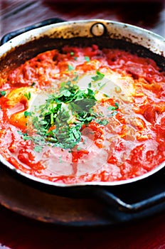 Shakshuka. Traditional jewish food and middle eastern cuisine recipe. Fried eggs, tomatoes, bell pepper and parsley in a