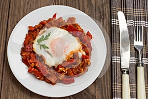 Shakshuka on a white plate. Traditional Jewish dish. Wooden table. Close-up