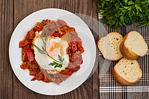Shakshuka on a white plate. Traditional Jewish dish. Wooden table. Top view. Close-up