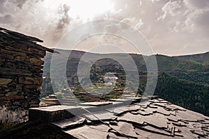 Shale stone tiles and stone chimney in PiodÃ£o village in contrast to mountain view in cloudy day, Arganil PORTUGAL