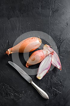 Shallot, eschalot or scallion raw ripe onions sliced and halved black background top view